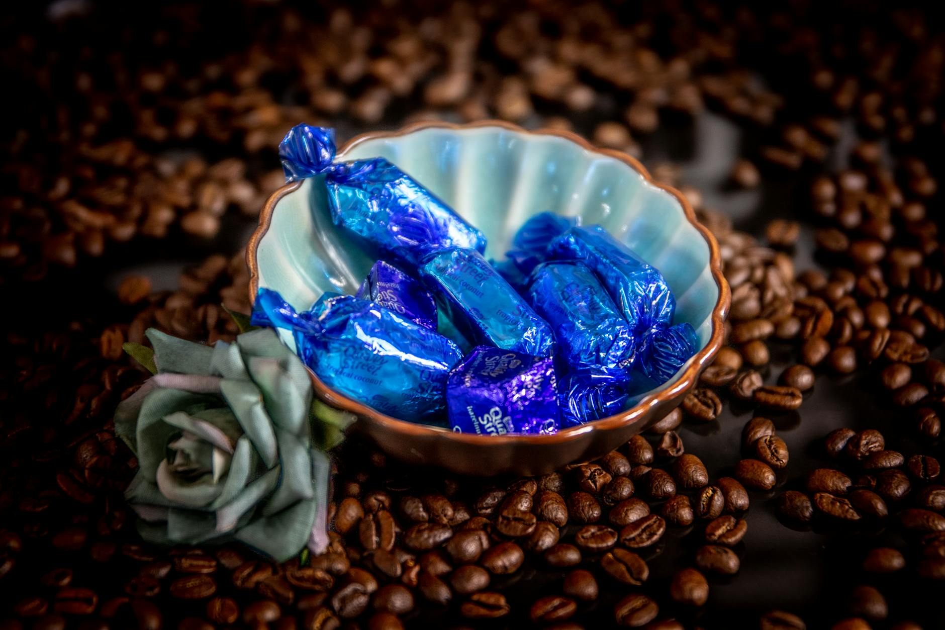 Candies in a blue wrapper blue wrapped candies inside a bowl beside flower