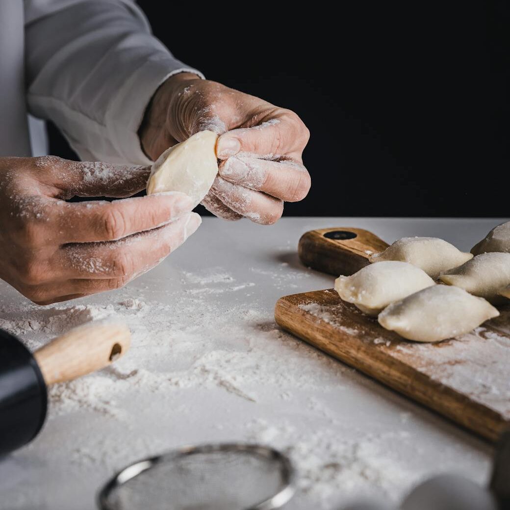 Handmade Perogies person holding brown wooden rolling pin