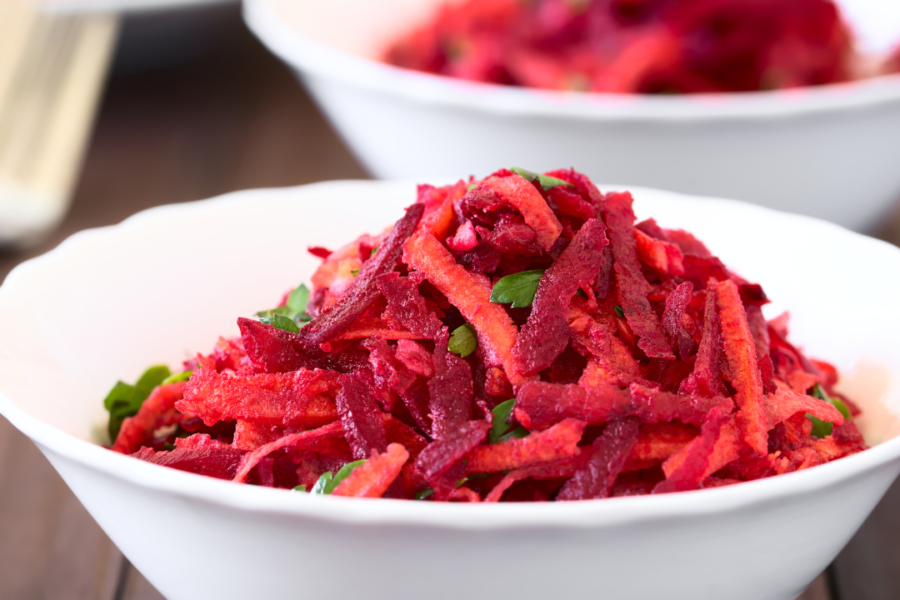 Vibrant red image of Beet Apple Coleslaw in a white bowl