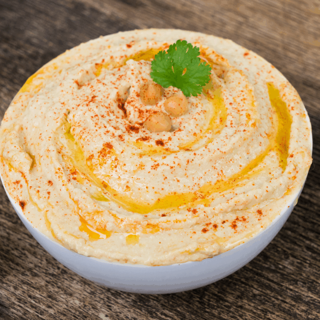 Image of a bowl of pumpkin hummus garnished with parsley.
